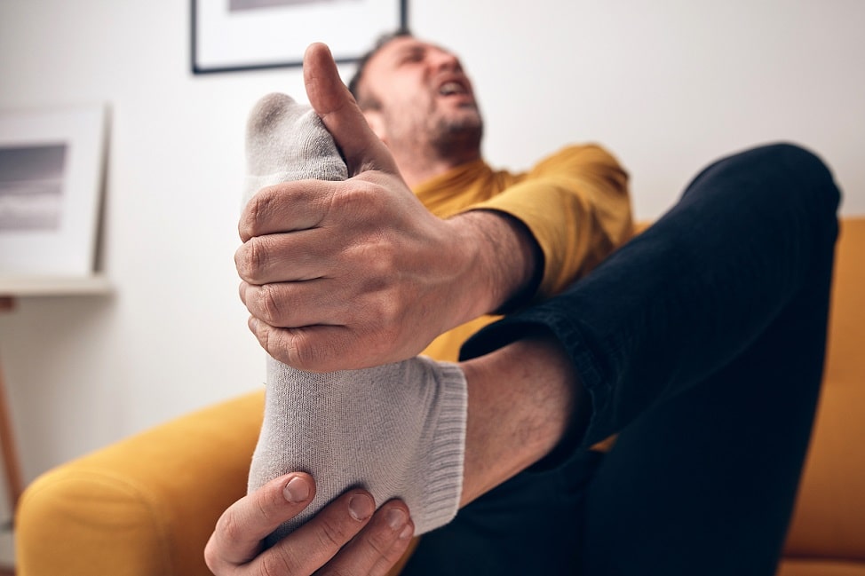 Man in pain holds his socked foot